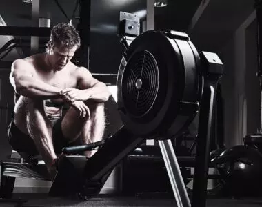 Athletic male resting after an intense workout in a dark industrial gym