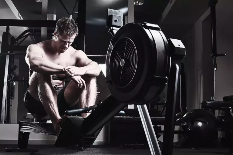 Athletic male resting after an intense workout in a dark industrial gym