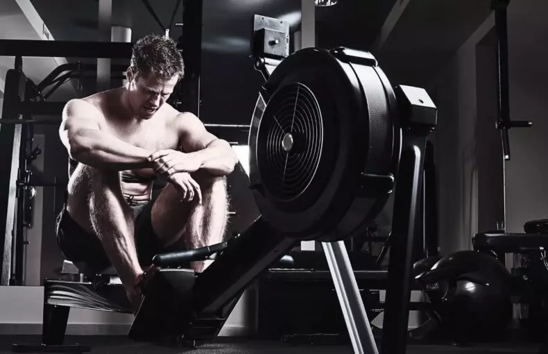 Athletic male resting after an intense workout in a dark industrial gym