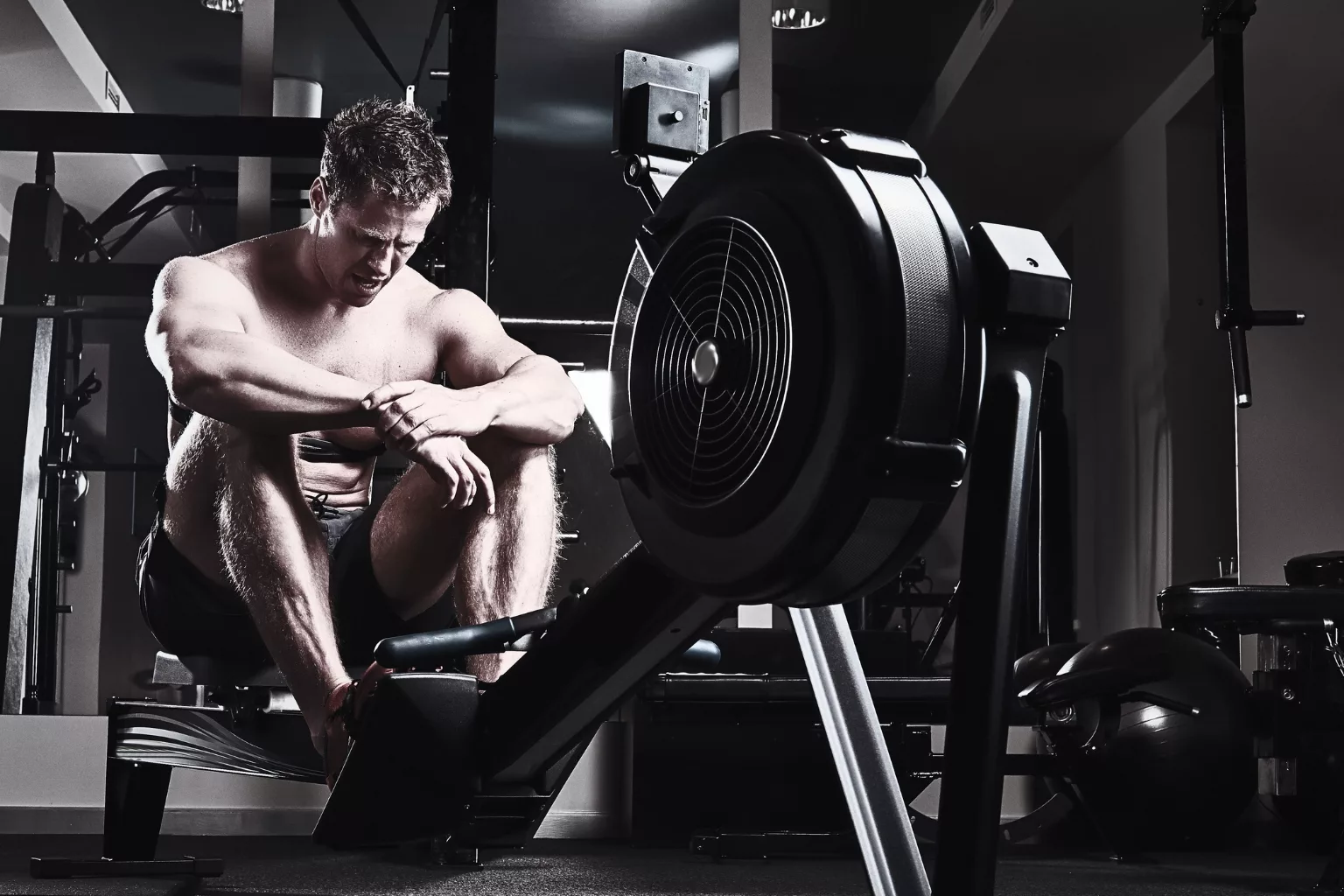 Athletic male resting after an intense workout in a dark industrial gym
